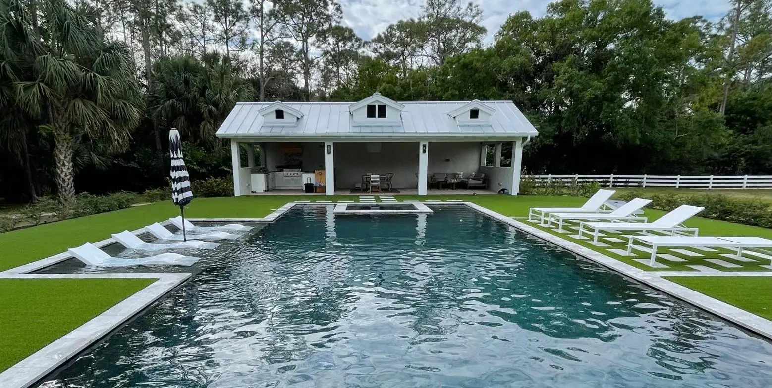 Long rectangular pool with in-water loungers on the sun shelf and a white cabana behind